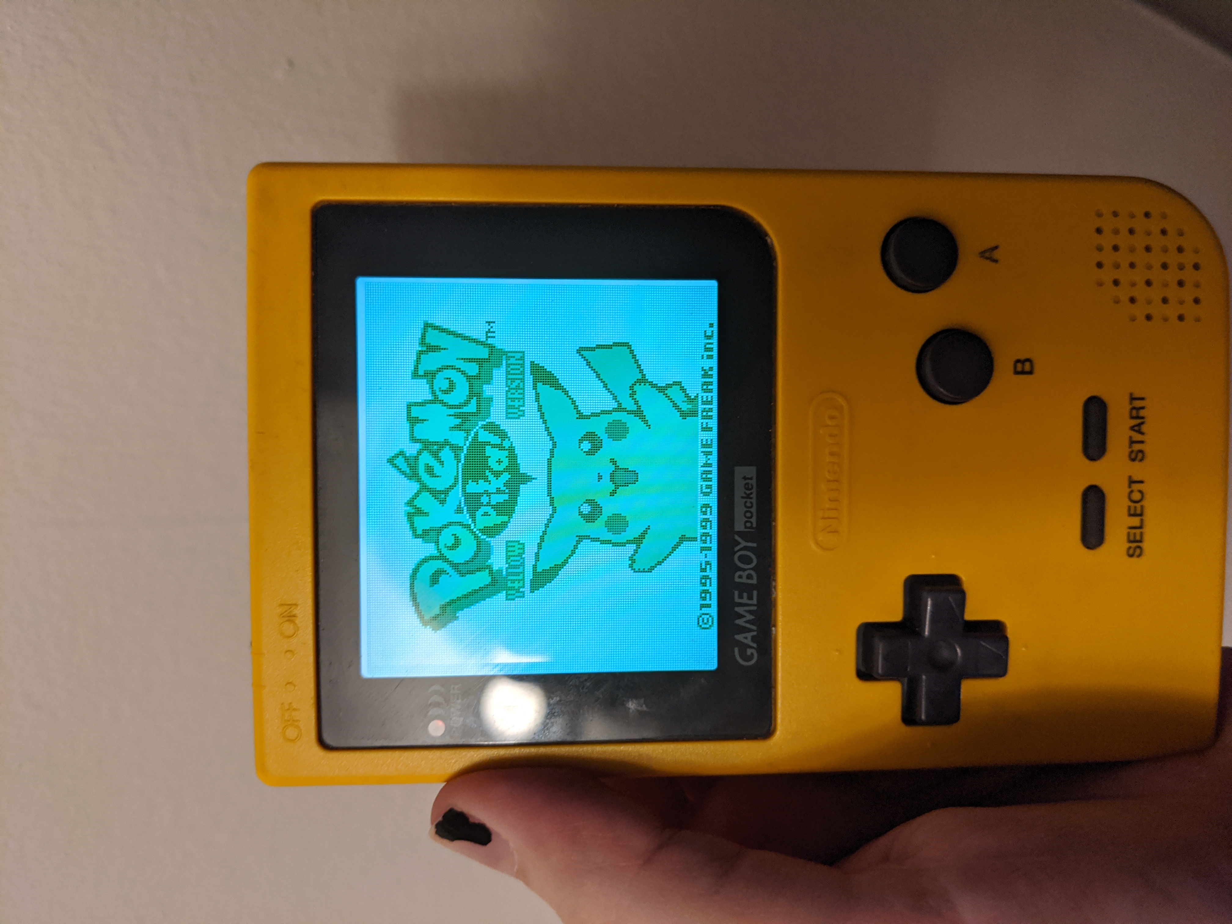 me holding a yellow gameboy pocket with a new screen and the start screen for pokemon yellow